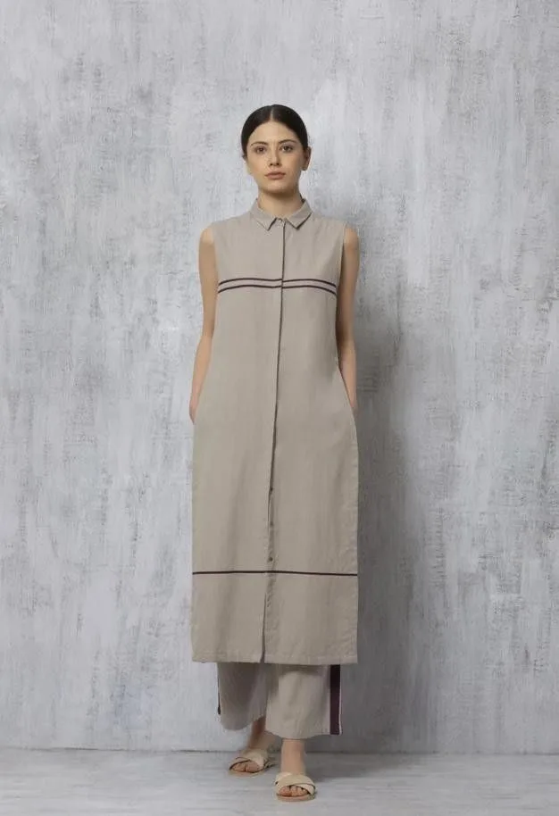 Woman in a sleeveless taupe shirt-dress with striped trim