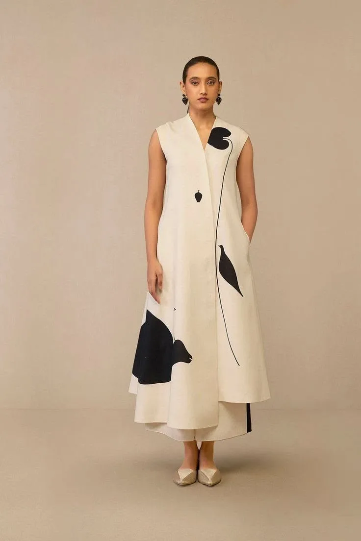 Woman in a cream sleeveless dress with a graphic bird print